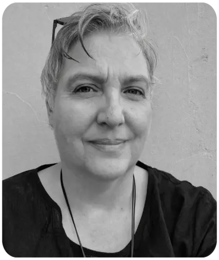 Schwarz-Weiß-Porträt von Colette Walter, Eventmanagerin bei Autismus Kunterbunt, lächelnd vor einer hellen Wand.